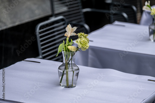 Flowers in a vase on a table on the veranda of a summer cafe.