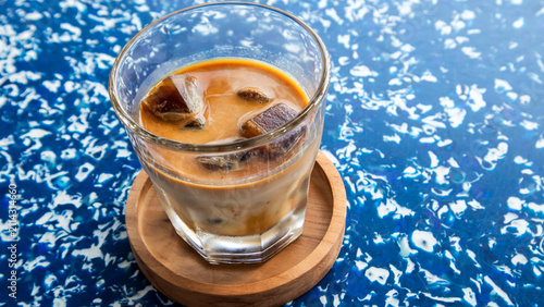 A glass of iced coffee latte on a table made from recycled materials
