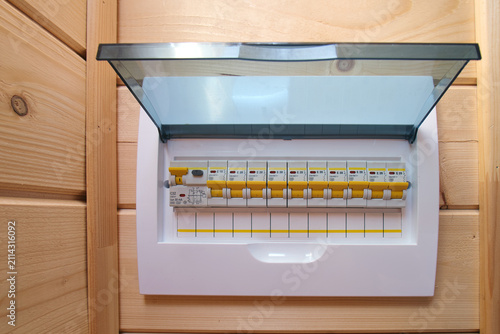 Electrical fuse box mounted on light wooden wall. Circuit breaker panel for residential power distribution. Safety device for home electric system, energy management and protection.