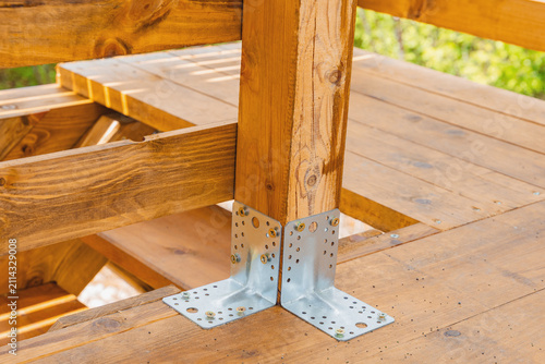 фотографія Metal post base bracket securing wooden post to deck during outdoor construction project