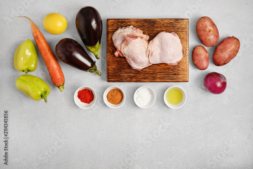 Cooking ingredients on gray surface with vegetables, chicken thighs and spices set for preparation