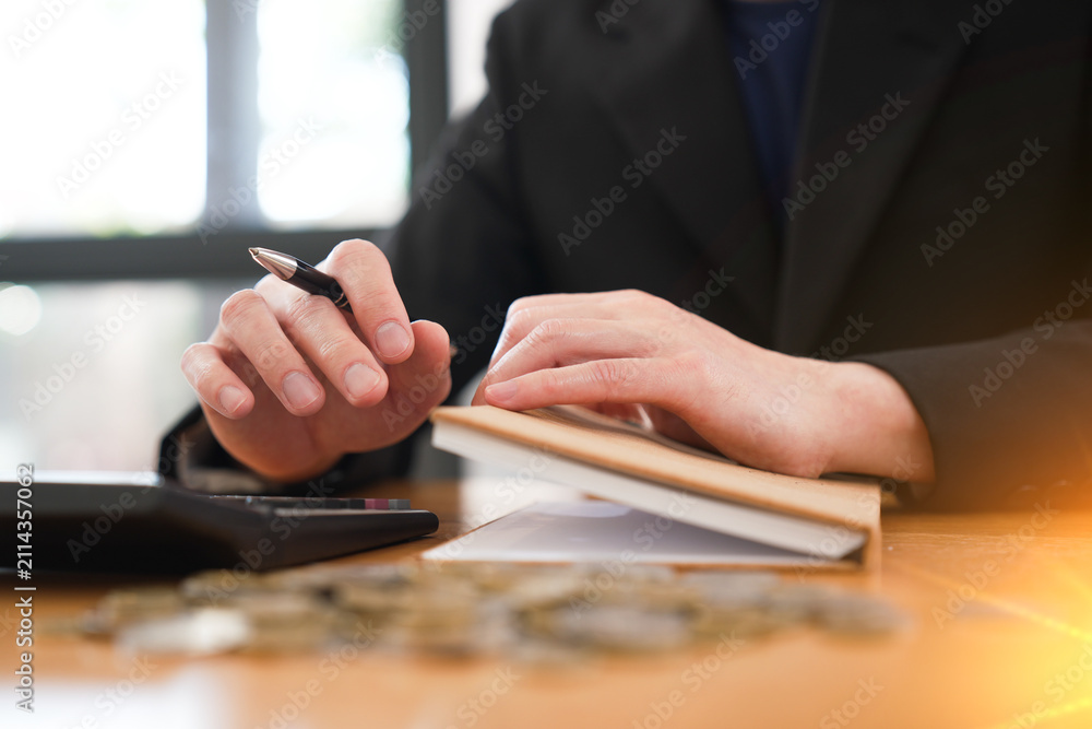 Fototapeta premium Close-up of a business professional reviewing financial notes while using a calculator with coins, representing budgeting, financial planning, accounting, savings, and investment management.