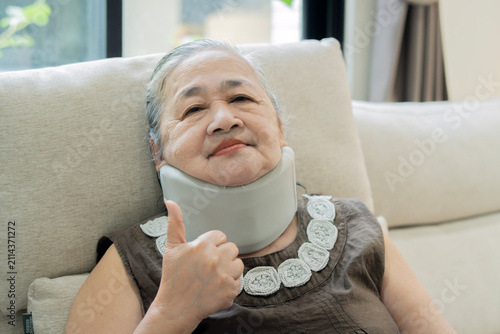Foto An Asian senior woman sitting on a couch and giving a thumbs-up sigh with a smil