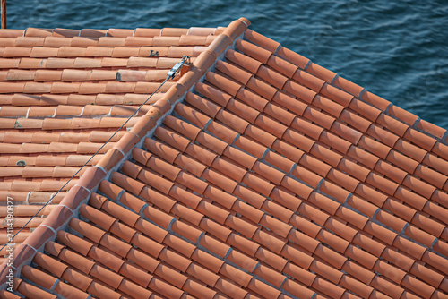 Close-Up Ridge Line of Terracotta Roof With Metal Bracket and Cable Against Sea