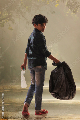 Young boy collecting garbage from the streets and helping the environment. (Children)