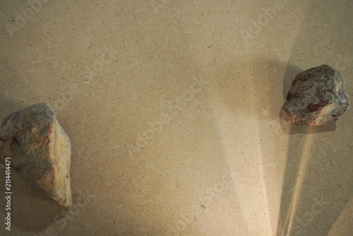 Natural stones and dramatic sunlight shadow on wooden board background with copy space.