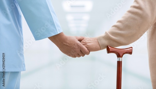 Caring hands gently clasp in a hallway, an elder's cane resting nearby