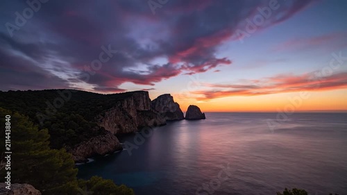 Golden sunset glows over rocky coastal cliffs and sea