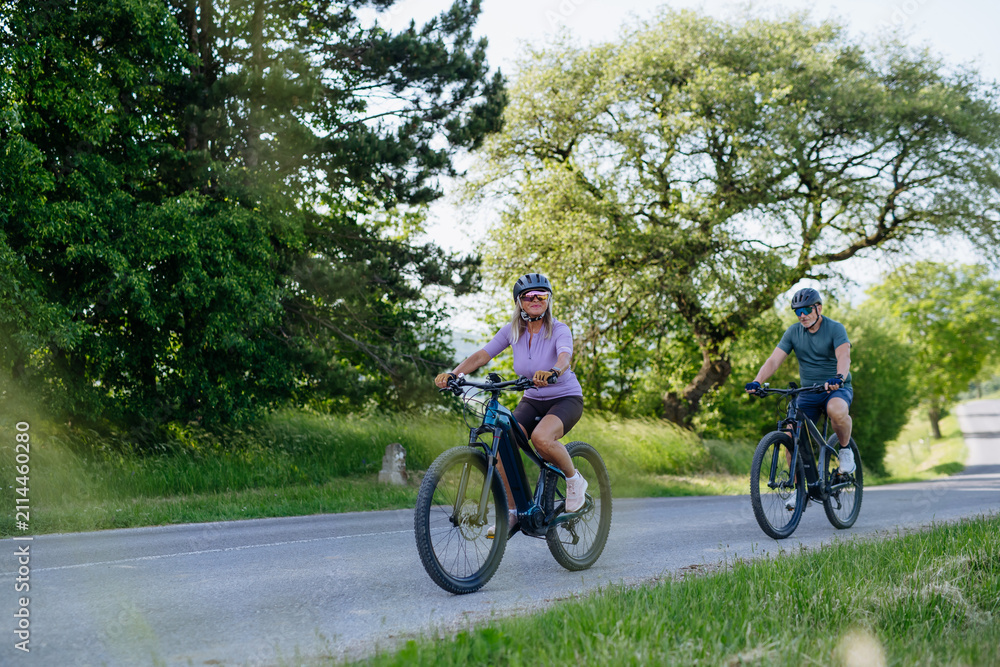 Fototapeta premium Active senior couple exploring nature on electric bicycles