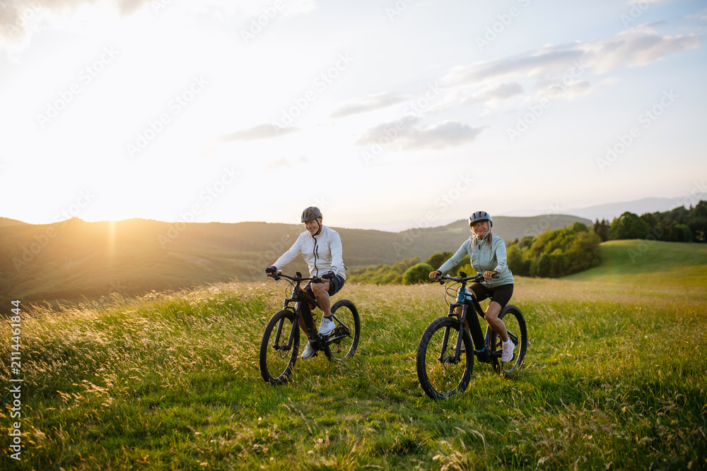Fototapeta premium Active senior couple exploring nature on electric bicycles
