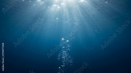 Sunlight rays streaming through deep blue ocean water with air bubbles rising to the surface from below
