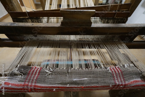 Close-up of a traditional wooden handloom weaving a patterned textile, showcasing heritage craftsmanship, textile production, folk art, and traditional craft techniques.