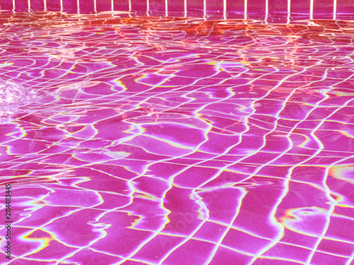 Vibrant pink swimming pool water with caustic light patterns and tiled bottom for aesthetic concepts and summer background designs.