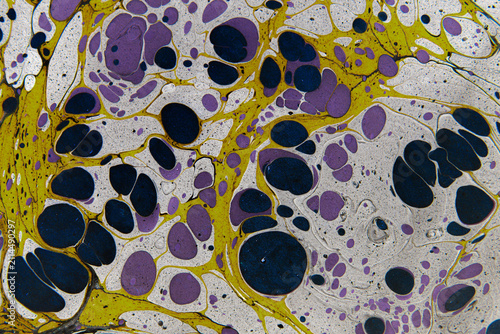 Abstract Ebru marbled paper pattern with yellow, purple and black fluid art drops for background design and creative texture.
