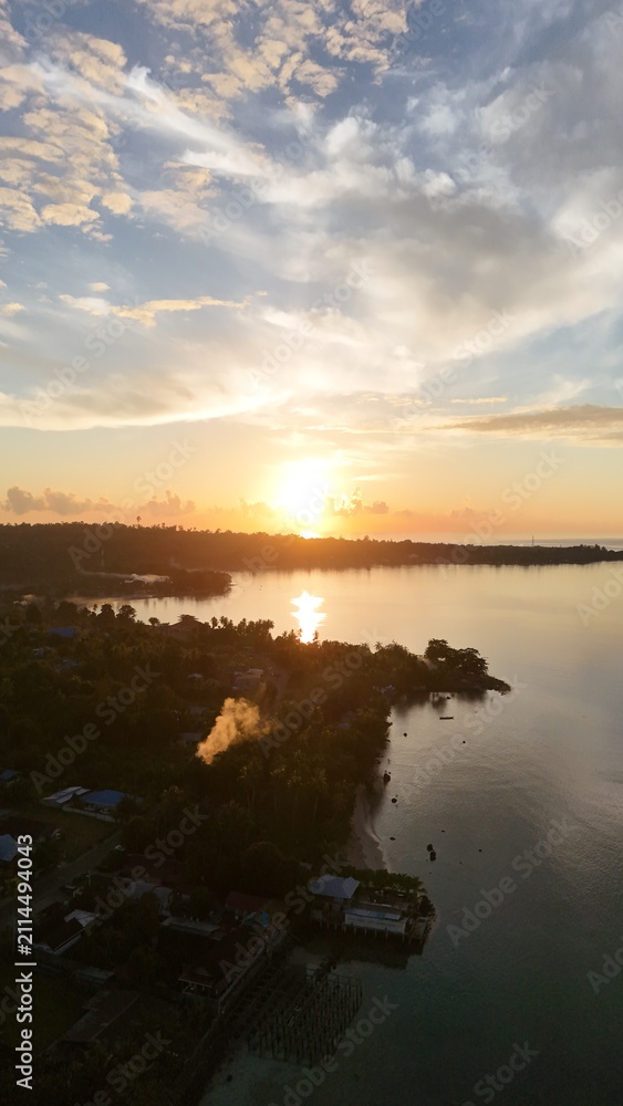 Fototapeta premium Vertical aerial sunrise over a tropical bay and island coast