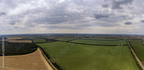 Aerial green and golden summer farmland patches with scenic cloudscape