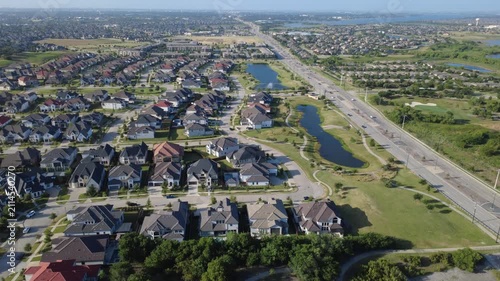Expansive flat roof retail structures sit alongside residential enclaves in rapidly expanding Dallas Fort Worth metroplex. Neighborhood access roads thread through properties in Frisco, Texas