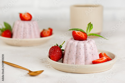 Fresh strawberry chia jelly dessert in rustic style with healthy ingredients and cup of tea.
