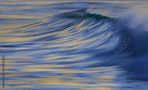 Foto Ocean wave at sunrise with spray at the crest at slow shutter speed