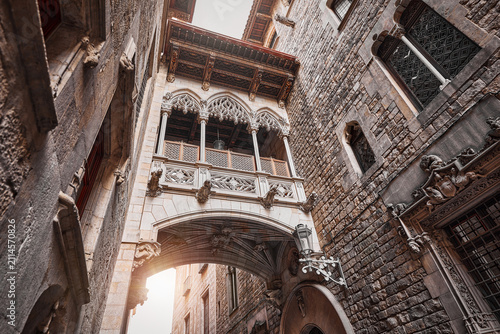 Barcelona, Spain. Barri Gotic Quarter. Antique Bridge between stone walls of medieval buildings in in old town. Famous touristic landmark and travel destination. Sunset evening street perspective.