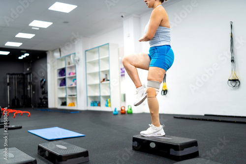 Adaptive woman stepping in gym, amputee athlete training for paralympic sport