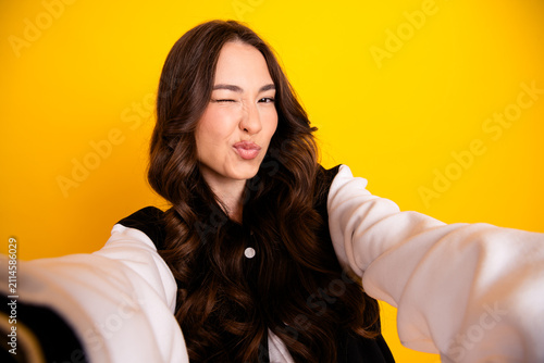 Quadro su tela Young woman taking a playful selfie winking and puckering lips against a bright