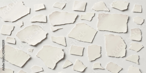 Scattered torn white paper fragments arranged randomly on light background creating abstract textured composition for design