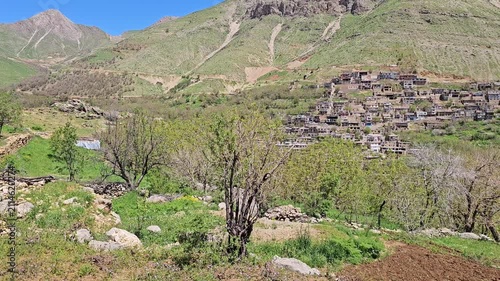 Lush spring orchard trees and a freshly tilled field lead toward a traditional mountain village nestled beneath rugged rocky peaks.
📍 Kamalla village, Hawraman Takht, Kurdistan 