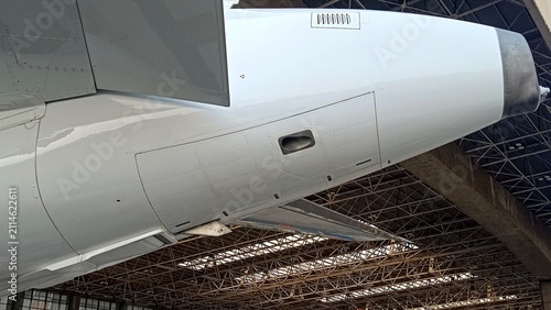 Close-up side view of an aircraft tail showcasing the external Auxiliary Power Unit (APU) exhaust on a commercial airplane. Aviation engineering, aerospace technology, and aircraft maintenance concept
