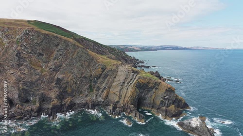 Aerial flight proceeding directly forward and flying over the massive, jagged sea cliff and dramatic rocky promontory at Fast Castle Head, Berwickshire, Scotland.