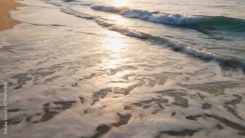 Sunlight reflecting on foamy waves rolling onto a sandy beach