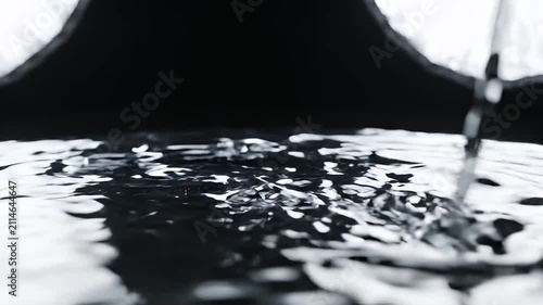 Water pouring into a surface of rippling water