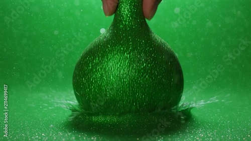 Green Spheres Falling into Liquid with Bubbles in Studio Lighting