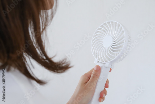 ハンディファンを使う女性の手元　暑さ対策