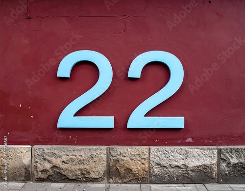 A red wall with a stone base and large blue number twenty-two