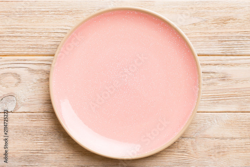 Top view of empty pink plate on wooden background. Empty space for your design