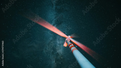 Low angle view of a wind turbine against a starry night sky with the milky way visible astronomy renewable universe landscape