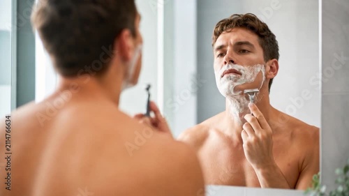 Young man shaving his beard.