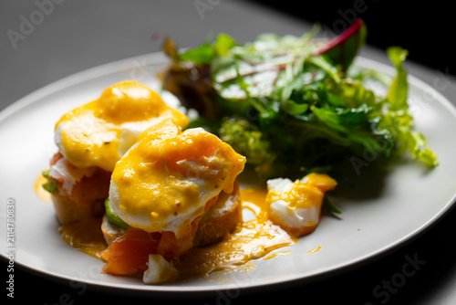 Foto Eggs benedict served with salad on a white plate