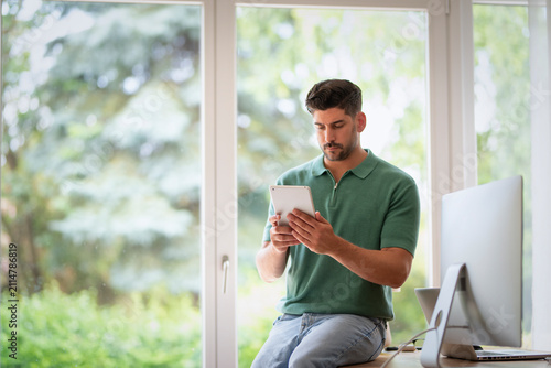 Handsome man using tablet by the window in a bright modern home
