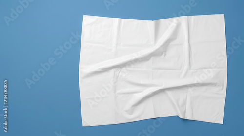 Crinkled White Paper Sheet Displayed on a Vibrant Blue Background Surface with Shadows and Folds