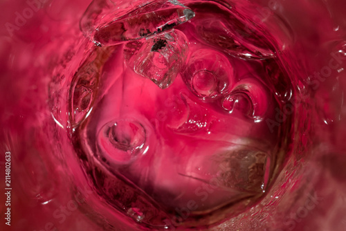 Obraz na płótnie Pink beverage with ice cubes in glass creating abstract reflections and cool tex