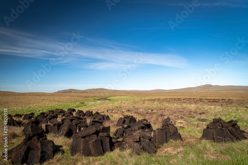 A warm, sunny HDR landscape image of freshly dug peat drying in the summer sunshine in Strathnaver, Sutherland, Scotland
