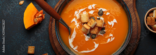 Pumpkin soup croutons cream fresh pumpkin slices wooden board dark background autumn winter