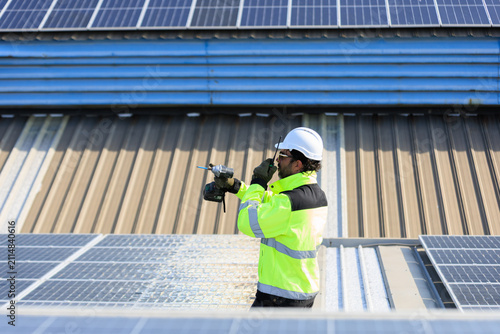 Solar technician communicating by radio while installing rooftop photovoltaic systems to support renewable energy, Net Zero and ESG goals through safe, efficient operations.