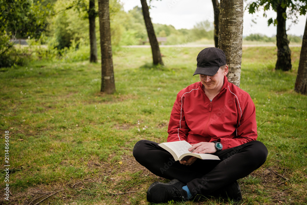 Obraz premium Man reading book relaxing in nature park