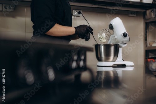 Pastry chef preparing dessert using kitchen mixer