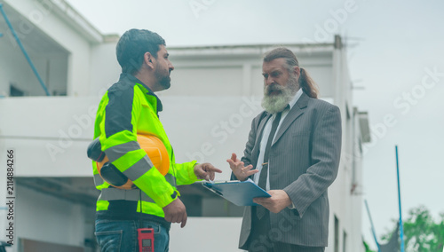 Angry businessman arguing with engineer over problem at house construction site outdoors