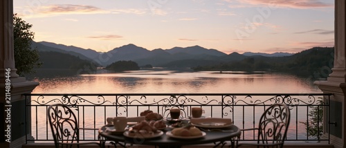 Breakfast on a balcony overlooking a lake. Morning meal with mountain view at sunrise.