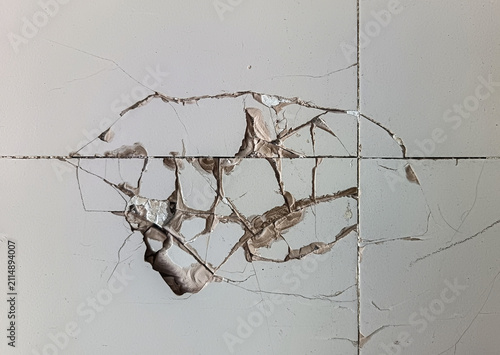 Broken white ceramic floor tile with visible cracks and damage. Home renovation, construction fault, floor repair, and property damage concept.